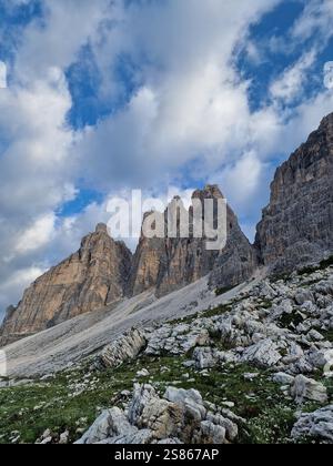 Splendida vista sulle aspre cime delle Dolomiti, forme affilate e frastagliate e superfici rocciose, lussureggiante erba verde, soffici nuvole, escursioni a tre Cime Foto Stock