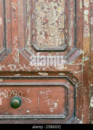 Nel cuore di Napoli, in Piazza Garibaldi, una porta in legno d'epoca è una silenziosa testimonianza dei ritmi sempre mutevoli della città. Foto Stock