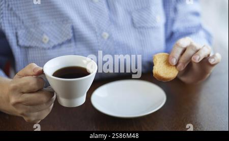 Mani di una donna anziana che tiene una tazza di caffè e biscotti, Belgio, Europa Foto Stock