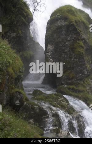 Ruscello che scorre in una gola su un lato di una potente cascata Foto Stock