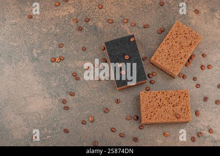 Set di spugne per lavare piatti. Concetto di pulizia biologico, aroma di caffè. Stile zero rifiuti, sfondo in pietra marrone caldo, posa piatta, vista dall'alto Foto Stock