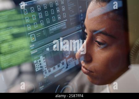Primo piano estremo di una programmatrice donna concentrata del Medio Oriente che guarda lo schermo del computer che lavora in ufficio, effetto a doppia esposizione Foto Stock
