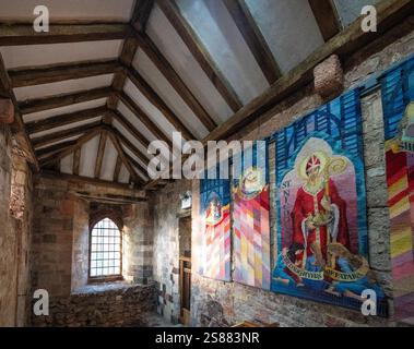 Le pareti sono appese in una scala del Priorato di San Nicola, l'edificio più antico di Exeter, Devon, Inghilterra, Regno Unito. Foto Stock