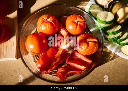 Una sapiente disposizione di verdure fresche e arrostite in un recipiente trasparente. Questa colorata esposizione culinaria include pomodori, peperoni rossi e S. Foto Stock