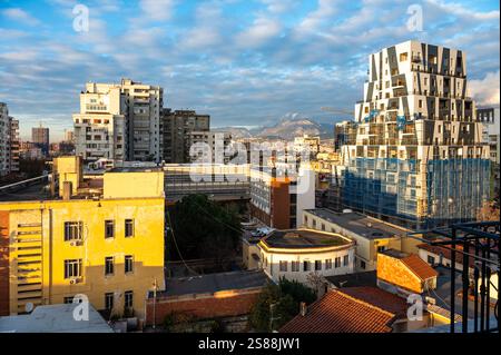 Vista dall'alto su edifici di appartamenti colorati e montagne al crepuscolo nella città di Tirana, Albania, 12 dicembre 2024 Foto Stock