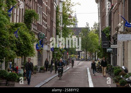 La gente pedala e cammina attraverso una piacevole strada dello shopping, Herenstraat, nel centro storico di Amsterdam. Foto Stock