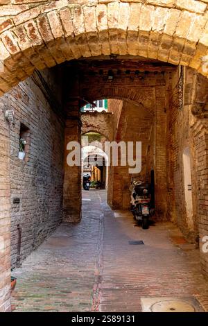 Stradina secondaria stretta con archi a Siena, Italia Foto Stock