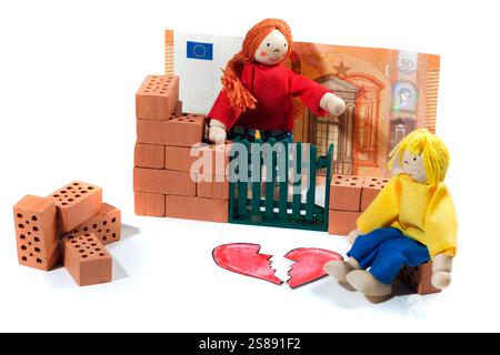 Natura morta con piccole bambole che raffigurano la separazione di una giovane coppia mentre costruiscono una casa con piccole figure di argilla e un cuore spezzato su bianco. Foto Stock