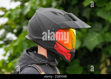 Una persona indossa un casco nero con occhiali rossi. La persona indossa anche una giacca nera Foto Stock