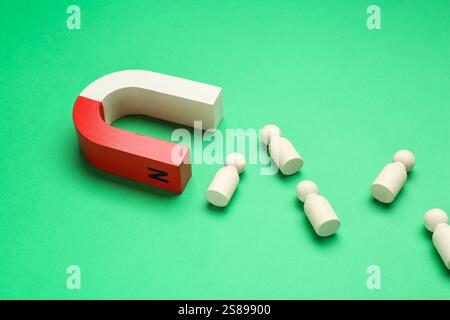 Magnete che attrae figure umane su sfondo verde Foto Stock