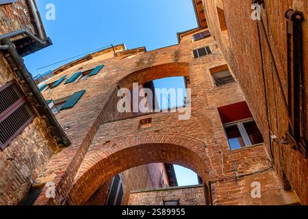 Collegando archi sopra la ripida stradina di via della Galluzza , una ripida stradina stretta con archi medievali a Siena, Italia Foto Stock