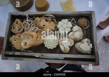 Saponi fatti a mano posti su un vassoio di legno, decorato con spugne di mare e nei vari ingredienti intorno ad esso come il favo Foto Stock
