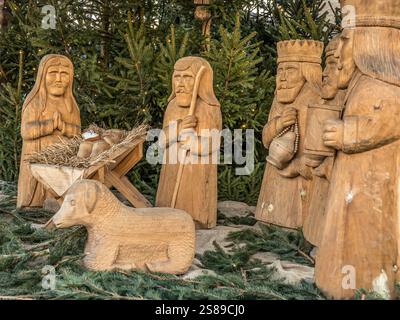 Presepe con sculture in legno che rappresentano la nascita di Gesù, circondato dal verde e simboleggia lo spirito natalizio. Le figure includono ma Foto Stock