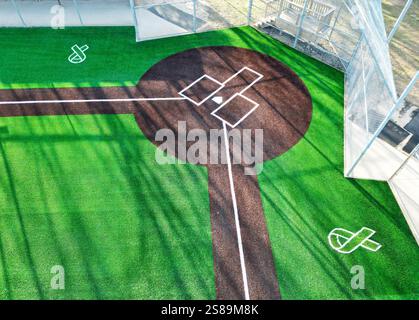 Il campo da baseball artificiale dai colori vivaci presenta erba fresca e segni chiari, catturati da una prospettiva aerea. Foto Stock
