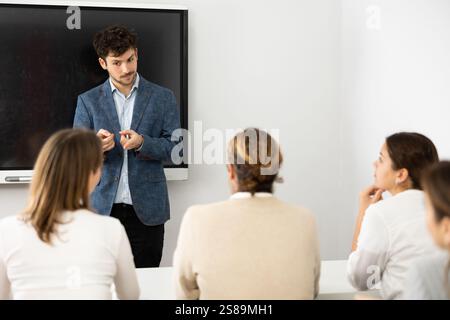 Insegnante giovane di sesso maschile che tiene lezioni a gruppo di studenti Foto Stock