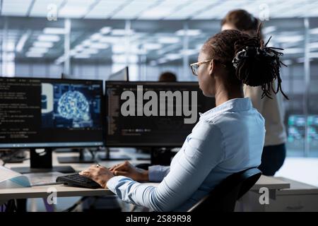 Donna che digita un computer in un server hub, che monitora il consumo energetico del data center utilizzando un software di intelligenza artificiale. Progettare la gestione dei supercomputer in sala server utilizzando la tecnologia dell'intelligenza artificiale Foto Stock