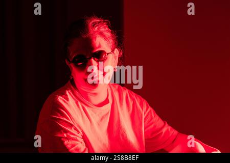 Primo piano di una donna anziana che indossa occhiali da sole durante la terapia a luce rossa in ambienti chiusi Foto Stock