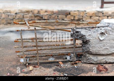 Barre di rinforzo in metallo arrugginito accoppiate con frammenti di calcestruzzo scheggiato. Deterioramento, decadimento, negligenza nello sviluppo delle infrastrutture o imp. Di corrosione Foto Stock