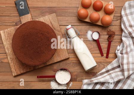 Deliziosa torta di spugne al cioccolato con ingredienti su fondo in legno Foto Stock