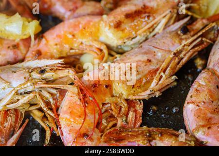 Gamberi grandi grigliati, longoustine cotti in una padella con spezie, erbe e limone su sfondo scuro. Foto Stock