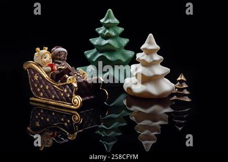 Cioccolatini a forma di figure natalizie su sfondo nero. Alberi di Natale, slitte, orsi al cioccolato. Regali di Natale. Foto Stock