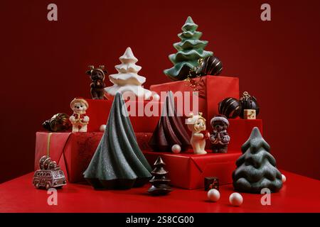Sfondo natalizio con scatole regalo e colorate figure di cioccolato con alberi di Natale, orsi e palle. Sfondo rosso Foto Stock