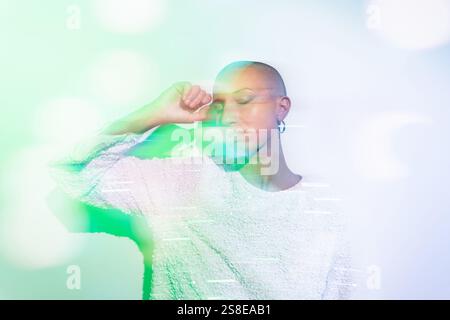 Un'immagine serena di una donna di mezza età con la testa rasata, che indossa un top bianco testurizzato su uno sfondo pastello morbido e sfocato, creando un'atmosfera da sogno Foto Stock