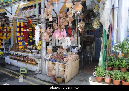 Una piccola fila di colorate ghirlande di fiori di Marigold in vendita e altri prodotti indiani nel quartiere di Little India a Singapore. Le ghirlande servono principalmente Foto Stock