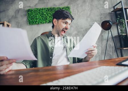 Giovane uomo d'affari che reagisce emotivamente ai documenti in un moderno loft Office Foto Stock