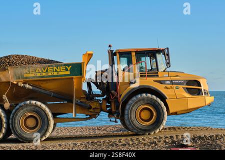 Eastbourne, East Sussex, Regno Unito - 16 gennaio 2025. Un dumper Volvo A30G su una spiaggia di ciottoli contro un cielo azzurro. Il trasportatore articolato Foto Stock