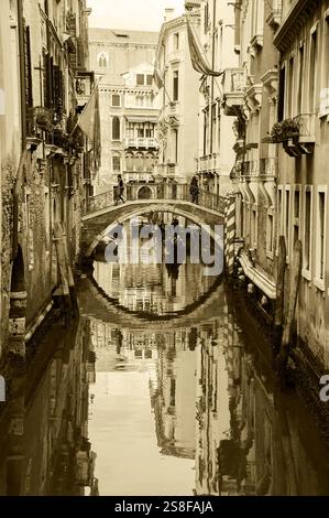 Tour in gondola a Venezia. Scena del canale. I turisti si godono un giro in gondola durante il Carnevale. Bandiere sulle case - veneziane, francesi. Venezia, Italia. Foto seppia Foto Stock