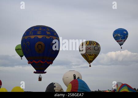 Una vivace scena di mongolfiere colorate che si lanciano simultaneamente in un cielo luminoso e limpido, per un momento spettacolare di avventura. Foto Stock