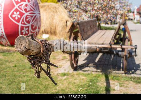 Un carrello in legno d'epoca esposto all'aperto, caratterizzato da dettagli rustici e circondato da decorazioni natalizie pasquali, tra cui un grande uovo dipinto. Foto Stock