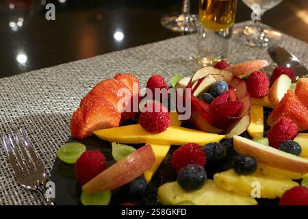 Vassoio di frutta artigianale con frutti di bosco freschi e fette tropicali in esposizione Foto Stock