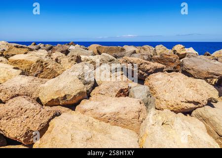 Grandi rocce costiere frastagliate contro l'orizzonte blu profondo dell'oceano sotto un cielo limpido e soleggiato. Gran Canaria, Las Palmas, Spagna. Foto Stock