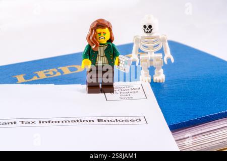Chappaqua, NY - 11 aprile 2024: Death and Taxes Concept Lego minifigure commercialista con calcolatrice, libro contabile, documenti fiscali Foto Stock