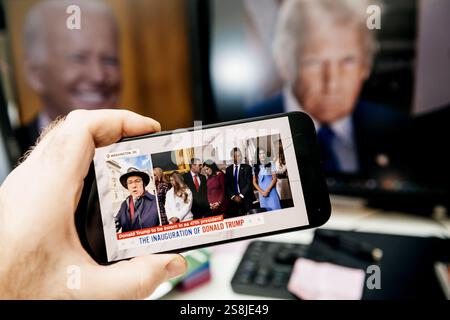 Parigi, Francia - 20 gennaio 2025: Una mano con uno smartphone che mostra la copertura dell'inaugurazione di Donald Trump come 47° presidente, con i partecipanti di fronte Foto Stock