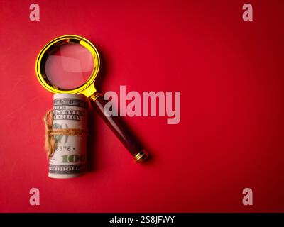 Banconote e lente d'ingrandimento vintage su sfondo rosso con spazio per copia e testo. Foto Stock