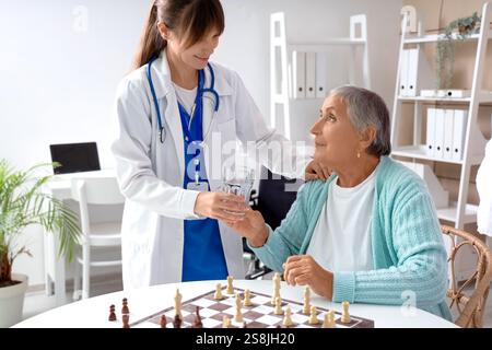 Donna anziana che prende un bicchiere d'acqua dal medico a casa di cura Foto Stock