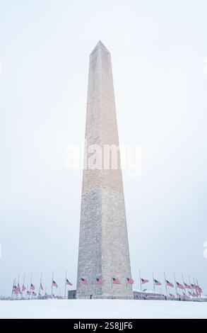 Vista del monumento a Washington in una giornata di neve con bandiere americane. Foto Stock