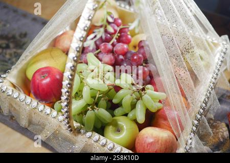 Un elegante cestino di frutta riempito con un delizioso assortimento di frutta fresca Foto Stock