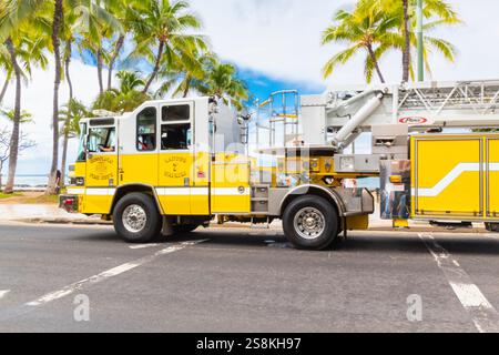 Honolulu, Hawaii, Stati Uniti - 22 febbraio 2024 - Un veicolo giallo brillante dei vigili del fuoco di Honolulu che viaggia lungo il lungomare di Waikiki, fornendo protezione antincendio Foto Stock