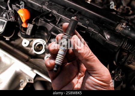 Primo piano della candela della vettura nella mano del meccanico , concetto di manutenzione della vettura Foto Stock