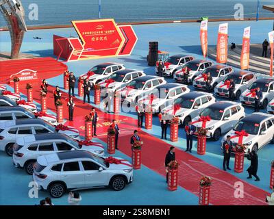 YANTAI, CINA - 23 GENNAIO 2025 - i dipendenti premiati posano per una foto con la vettura premiata durante la cerimonia di premiazione del gruppo Jierui 2024 'Go Foto Stock