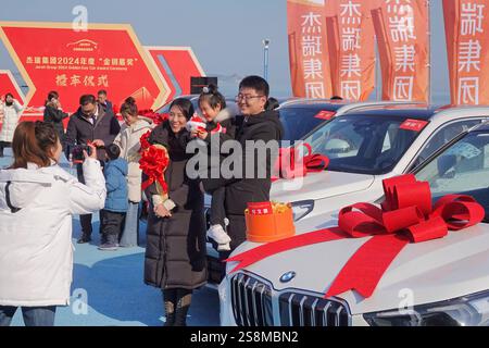 YANTAI, CINA - 23 GENNAIO 2025 - i dipendenti vincitori scattano una foto con le loro famiglie accanto all'auto premiata durante la cerimonia di premiazione di Jierui Gro Foto Stock