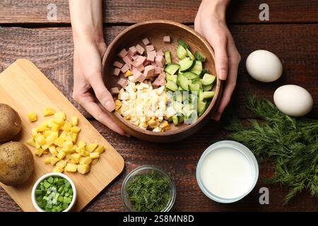 Donna che prepara zuppa di okroshka al tavolo di legno, vista dall'alto Foto Stock Donna che prepara zuppa di okroshka al tavolo di legno, vista dall'alto Foto Stock