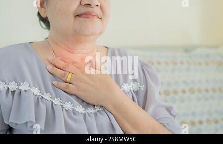 Donne asiatiche anziane malate che toccano il collo mal di tosse con mal di gola, cancro ai polmoni. Copia spazio. Foto Stock