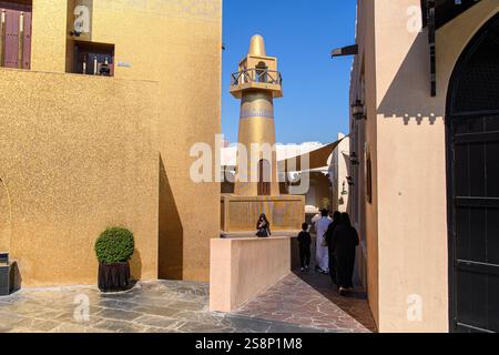 Doha, Qatar - 4 gennaio 2025: Un minareto dorato si erge in primo piano nel Katara Cultural Village, che mostra l'intricata architettura e la cultura Foto Stock