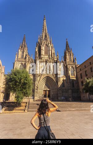 Giovane donna che contempla la splendida architettura gotica della cattedrale di barcellona in un giorno d'estate soleggiato, abbracciando il ricco patrimonio culturale di c Foto Stock