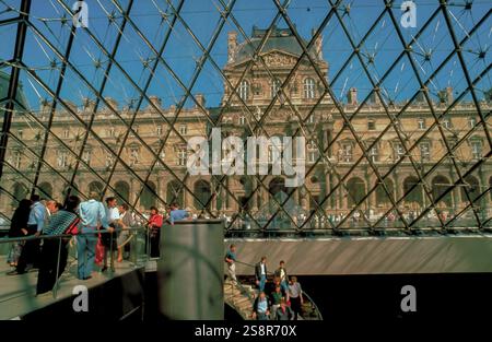 Parigi, Francia: Affollano persone, turisti che visitano all'interno della Piramide di vetro del Museo del Louvre, vista ad ampio angolo Foto Stock